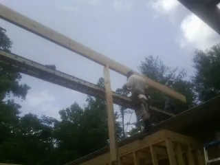 Carpenter setting a ridge beam over a new addition frame — Ice Dam Removal by Roofing Brothers in Snover