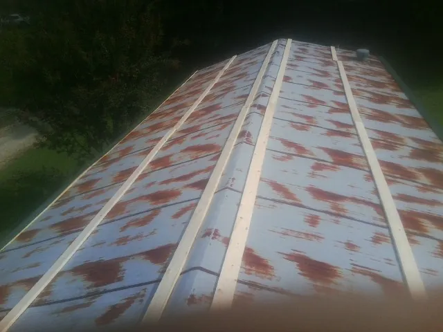 Rusted metal roof panels with new wood purlins before replacement — Storm Damage Roof Repair in Snover by Roofing Brothers