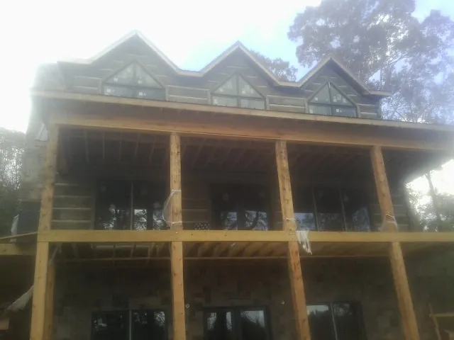 Dormers and porch framing on a large log home under construction — Roof Coating work by our crew in Snover