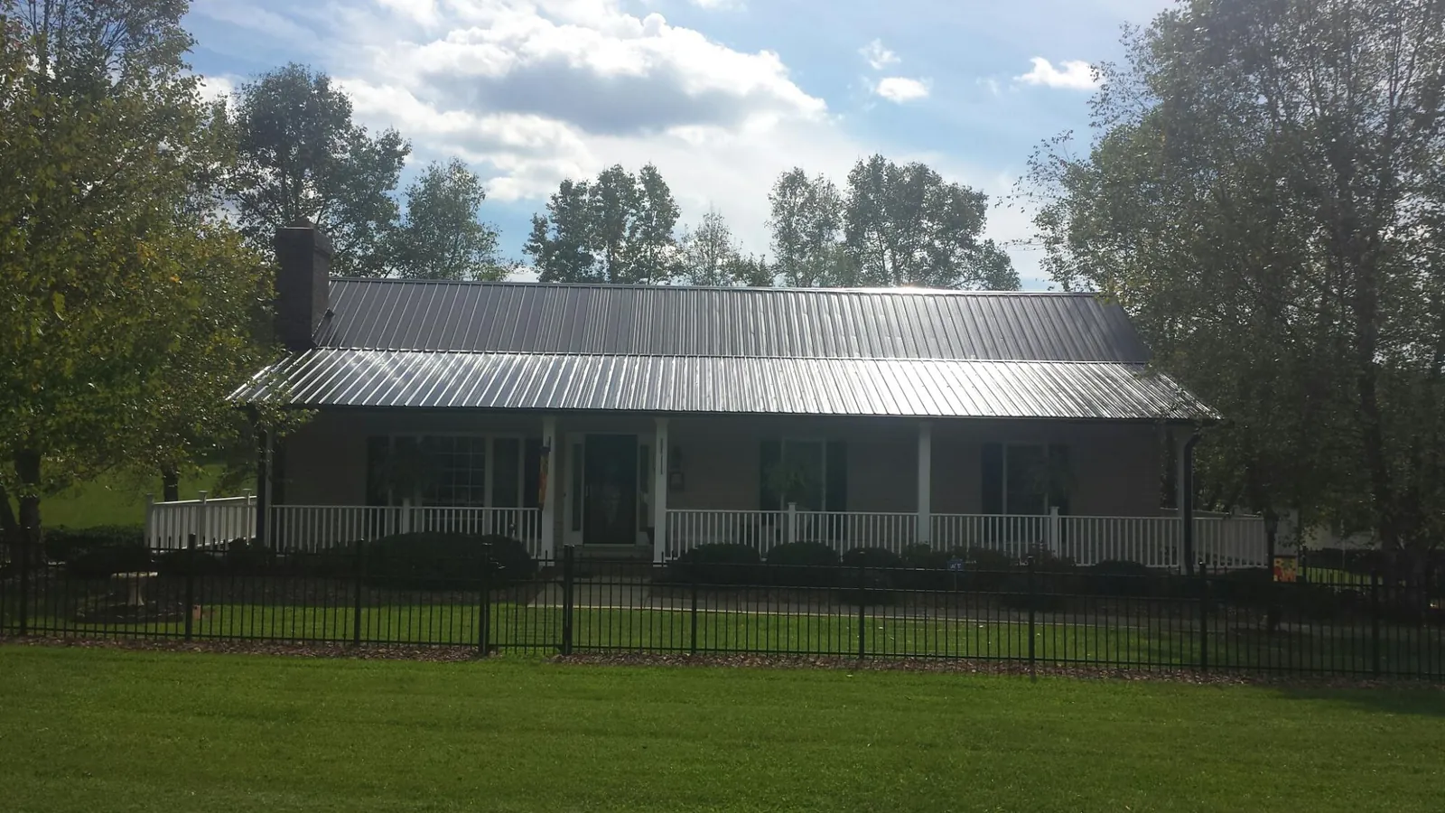 Gray metal roof on a brick ranch with a full width front porch — Gutter Guard Installation work by our crew in Snover