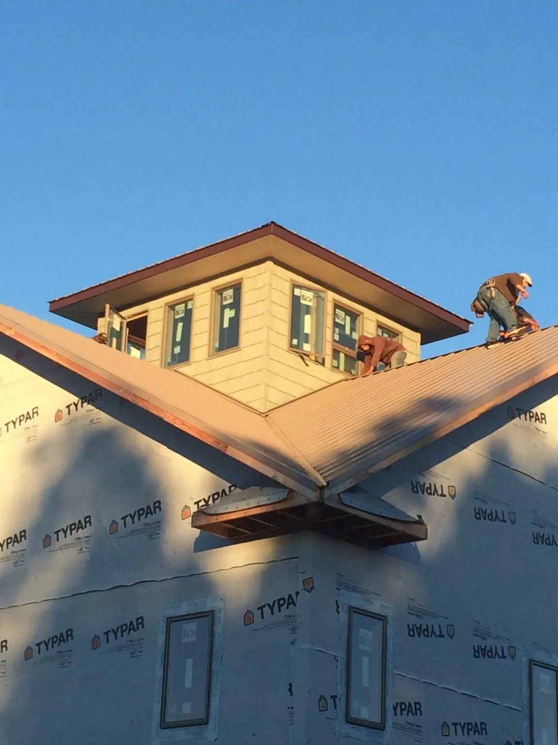Roofers working around a rooftop cupola on a new metal roof at sunset — Roof Waterproofing in Snover by Roofing Brothers